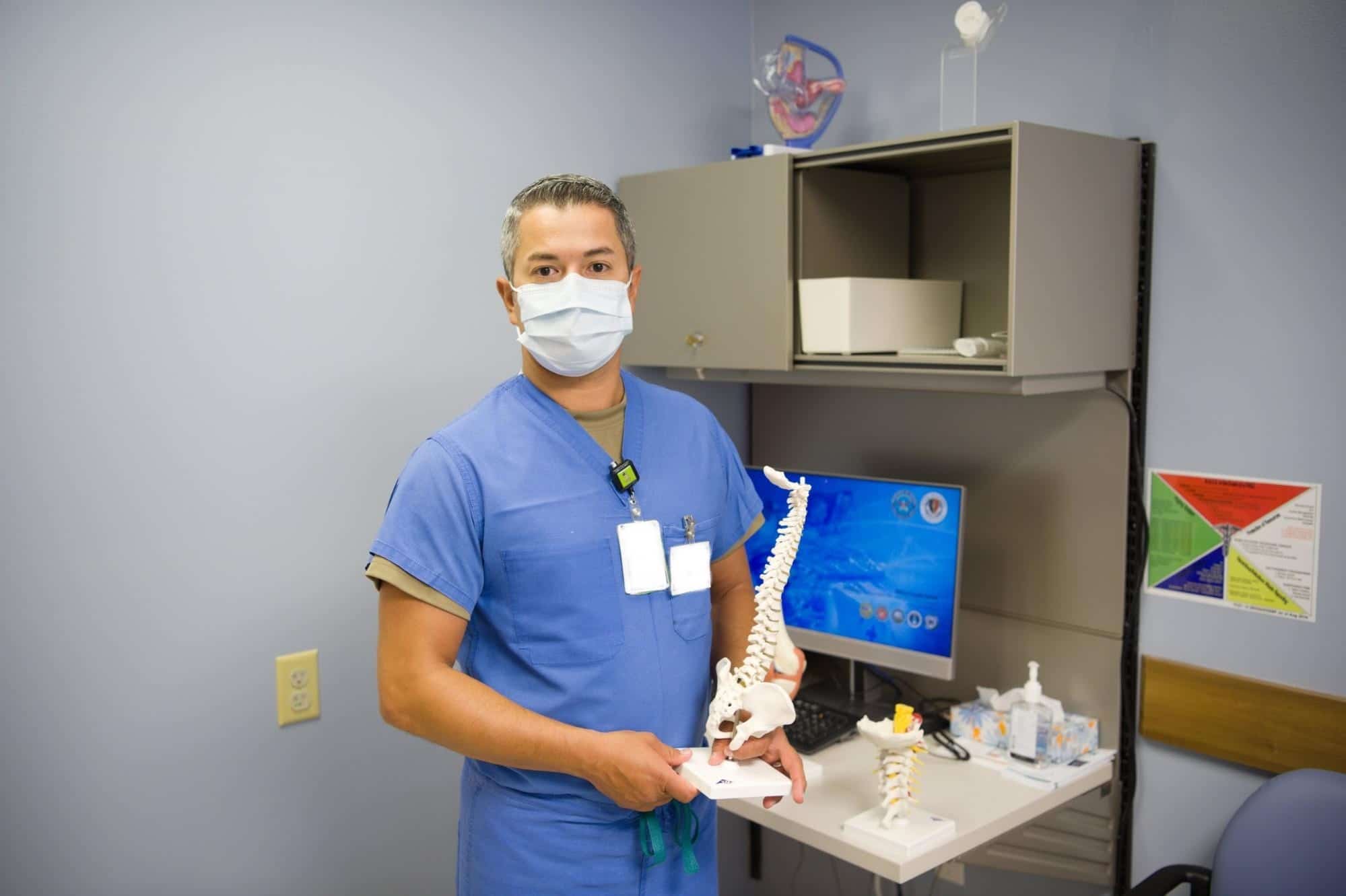 Masked healthcare professional with a model of the spine