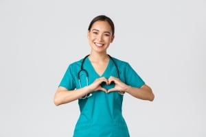 Smiling Asian nurse forming a heart with her hands