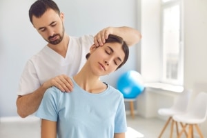 Physical therapy professional manipulating a woman's neck and shoulders