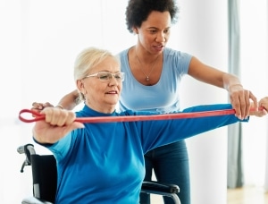 African-American medical professional helping a woman use an exercise band