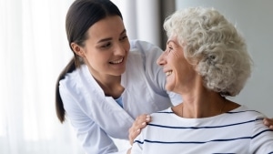 Elderly woman smiling at a young nurse over her shoulder