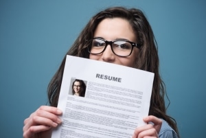 Woman with glasses holding up her resume