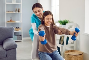 Physical therapy professional helping a young girl lift weights