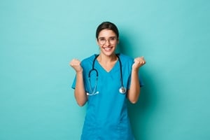 Smiling nurse holding her fists up against a solid backdrop