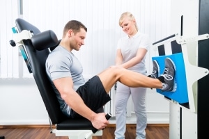 Physical therapy professional helping a male athlete use equipment