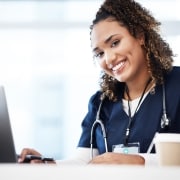 Smiling African-American nurse typing on a laptop